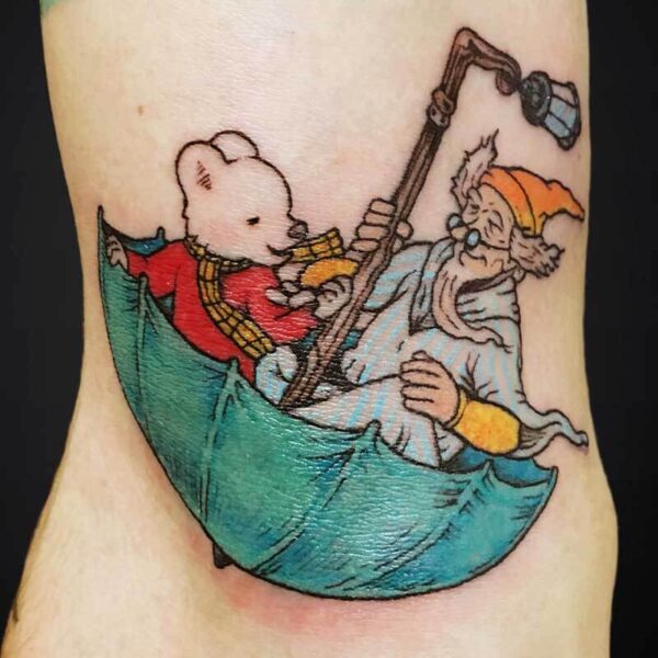 Cartoon tattoo on the leg showing Winnie the Pooh and an old bearded man in a small green boat at sea.