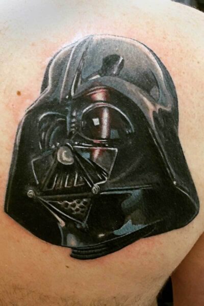 Tattoo of Darth Vader's helmet on a person's skin, dark and glossy with details of the mask.