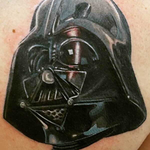 Tattoo of Darth Vader's helmet on a person's skin, dark and glossy with details of the mask.