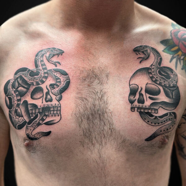 Twin skull tattoo designs on the chest, each with a snake winding around it, in black and gray ink.