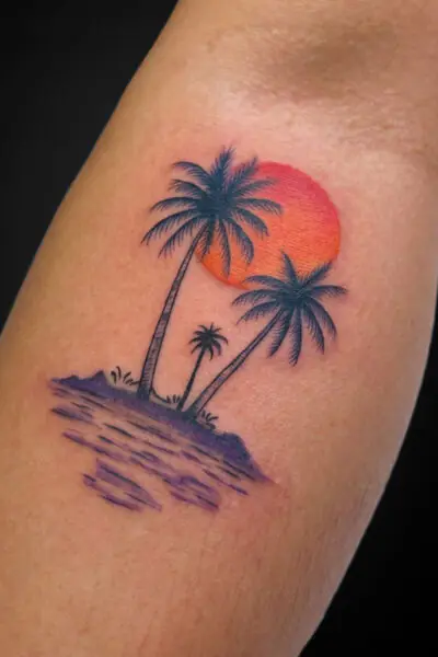 Tattoo of a tropical island with three palm trees, purple water, and an orange sunset behind them on the skin.