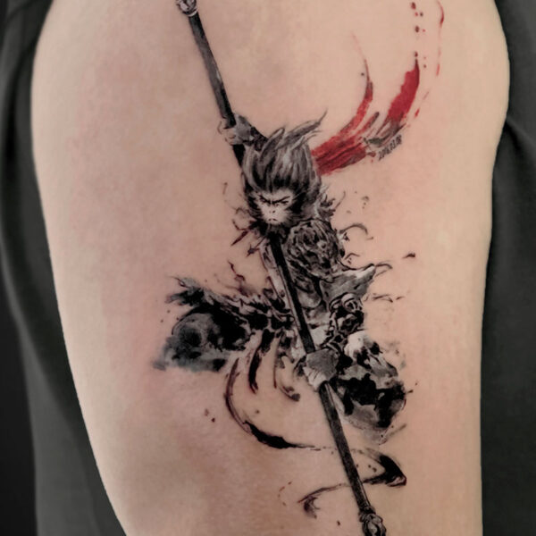 Watercolor-style black and gray tattoo of a samurai wielding a long katana, with red brushstrokes behind, on upper arm.