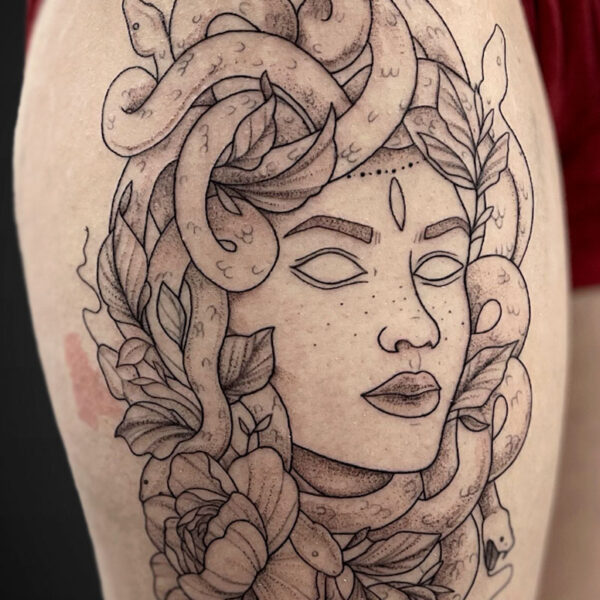 Tattoo design of a woman's face surrounded by curling snakes and leafy flowers.