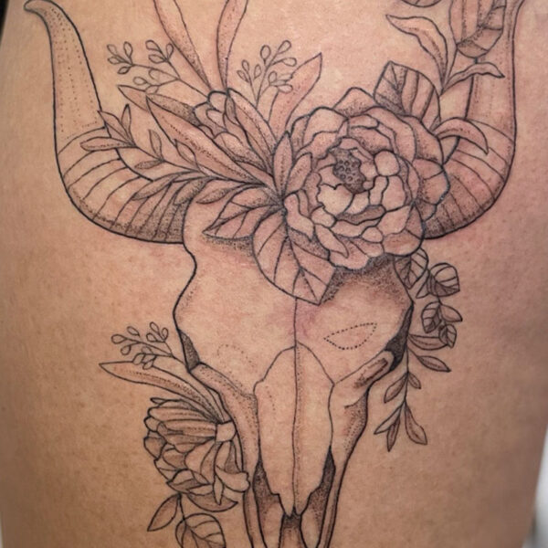 Bull skull with long curved horns, adorned by a bouquet of flowers and leaves around and across the horns.