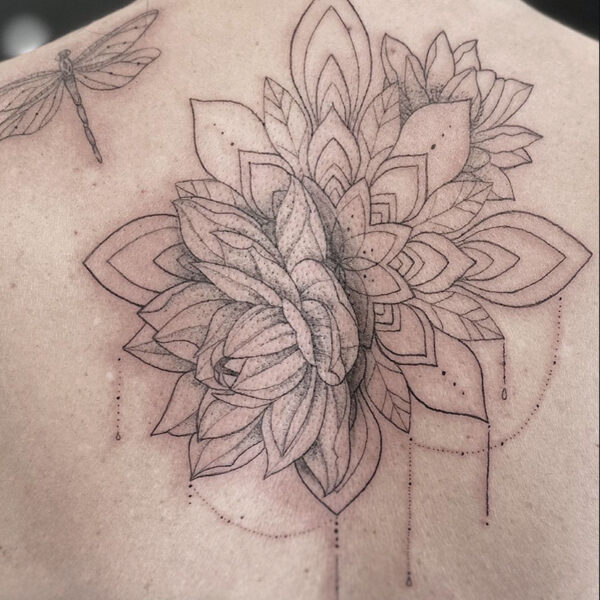 Back tattoo featuring a large geometric floral mandala cluster with layered petals and a small dragonfly outline on the left shoulder blade.