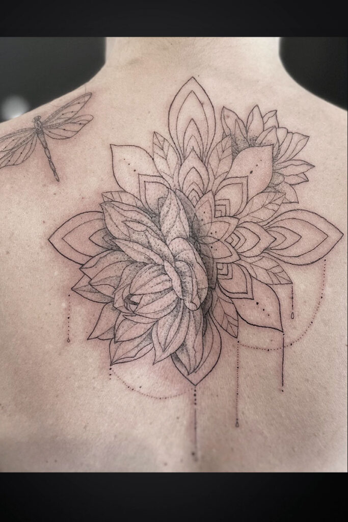 Back tattoo featuring a large geometric floral mandala cluster with layered petals and a small dragonfly outline on the left shoulder blade.