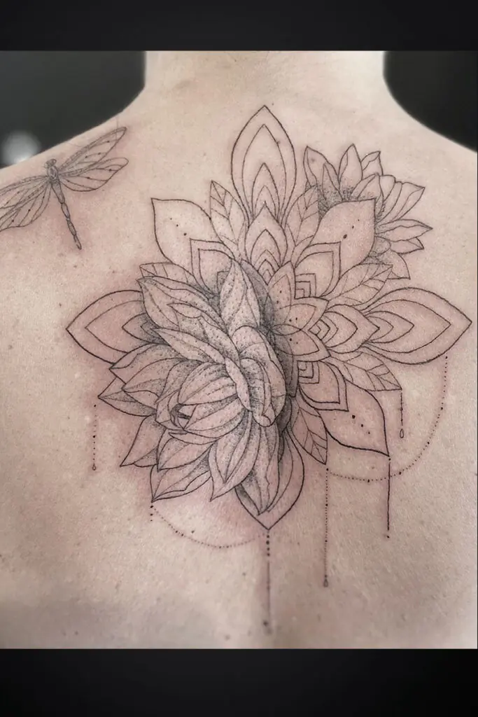 Back tattoo featuring a large geometric floral mandala cluster with layered petals and a small dragonfly outline on the left shoulder blade.
