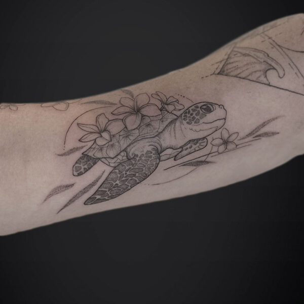 Forearm tattoo of a line-drawn turtle among flowers in black ink.
