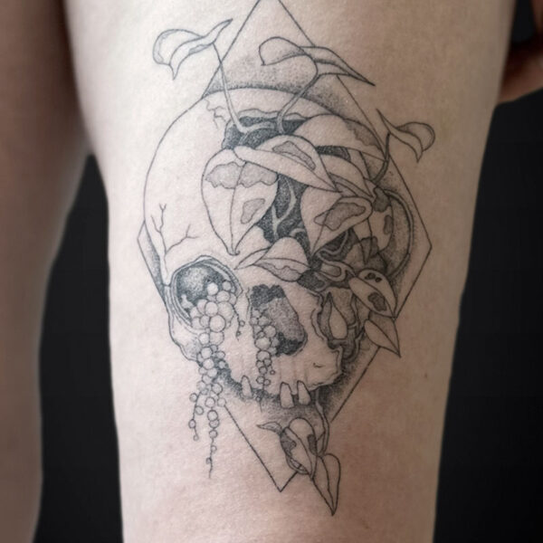 Black-and-gray skull tattoo entwined with vines inside a diamond outline.