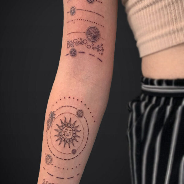 Cosmic-themed forearm tattoo with a sun at the elbow and planets on dotted circular orbit lines along the arm.