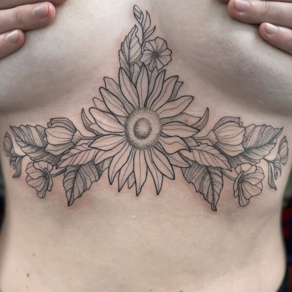 Tattoo across the chest: a large central sunflower with surrounding buds and leaves extending to the sides, resting on the ribcage.