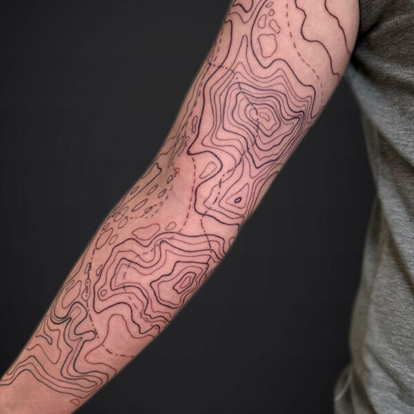 Forearm tattoo featuring abstract contour lines like a topographic map across the skin.
