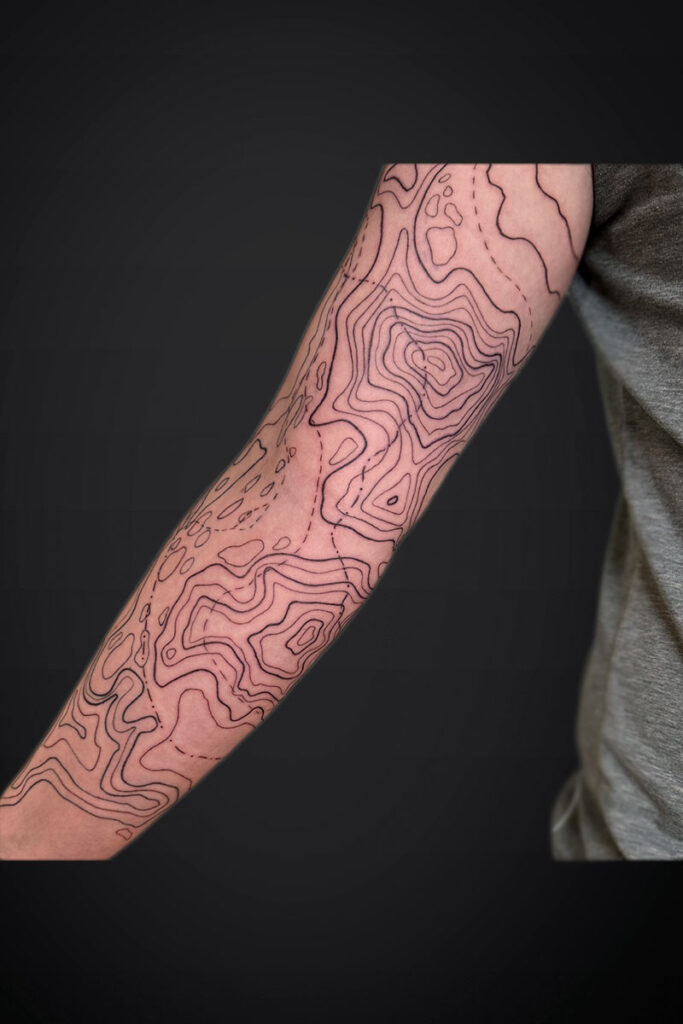 Forearm tattoo featuring abstract contour lines like a topographic map across the skin.