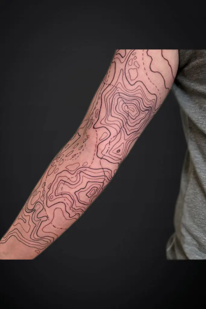Forearm tattoo featuring abstract contour lines like a topographic map across the skin.