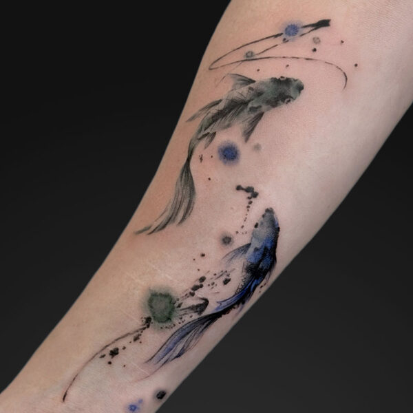 Watercolor-style koi fish tattoo on the forearm with blue and green ink splashes