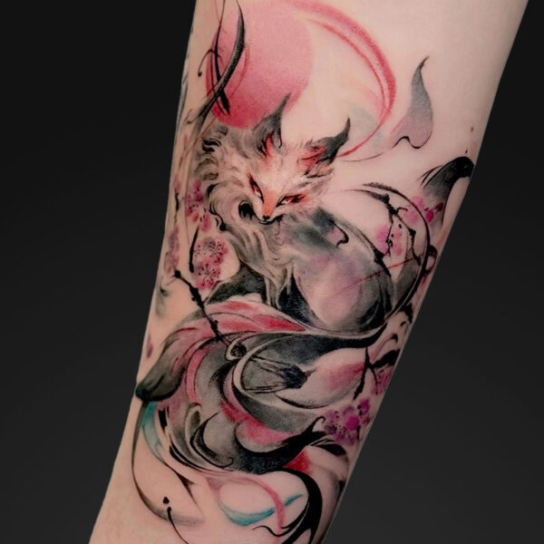 Colorful watercolor-style fox tattoo wrapping around a forearm, with pink blossoms and abstract black lines.