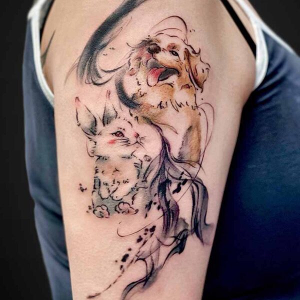 Watercolor-style tattoo of a happy dog and a cat on a person's upper arm.