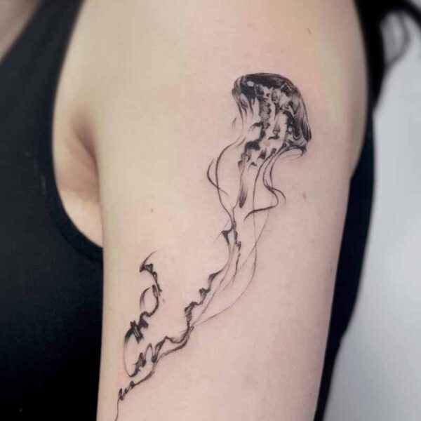 Delicate line tattoo of a jellyfish along the upper arm, with flowing tentacles and soft shading.