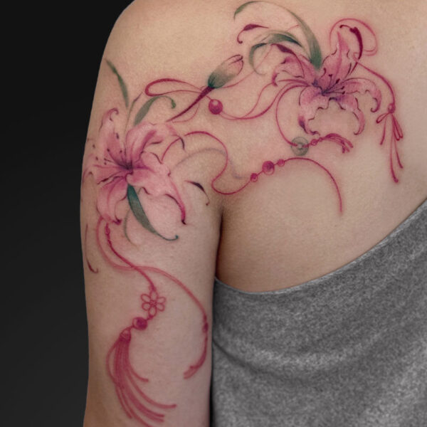 Pink watercolor-style floral tattoo wrapping from shoulder to upper arm, featuring lilies and flowing vines.