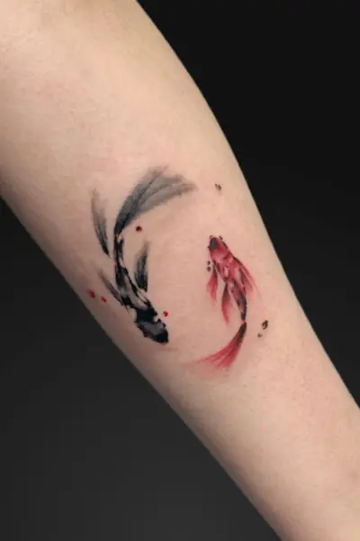 Watercolor-style koi fish tattoo in black and red on a forearm, depicted in a curved, flowing loop with splashes of red.