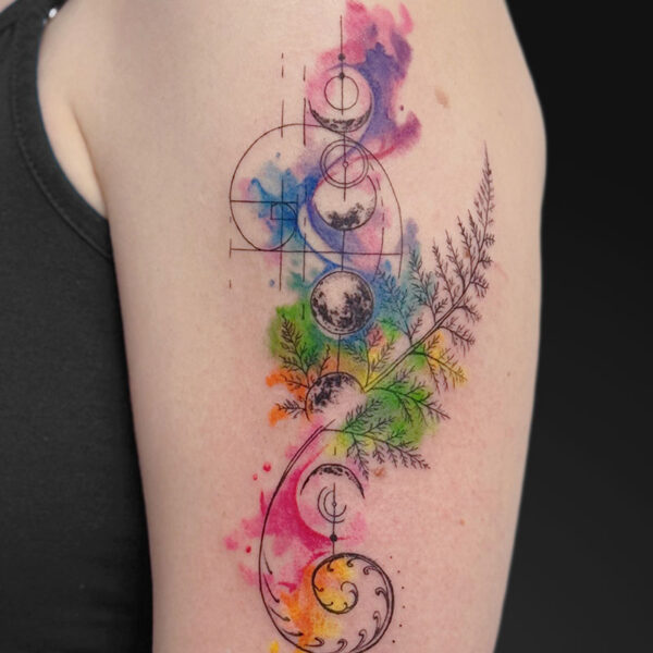 Watercolor-inspired tattoo on upper arm with geometric circles and aspiral moon motif connected to colorful branch-like plants.